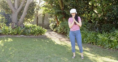 Asian Woman Enjoys Outdoor VR Experience in Sunny Garden