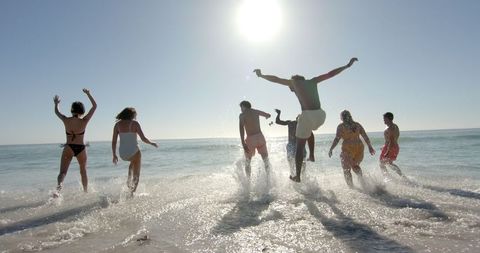 Diverse Friends Enjoying Sunny Beach Day with Laughter and Splashes - Download Free Stock Images Pikwizard.com