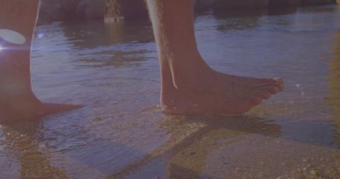 Bare Feet Wading in Tranquil Sea at Golden Hour