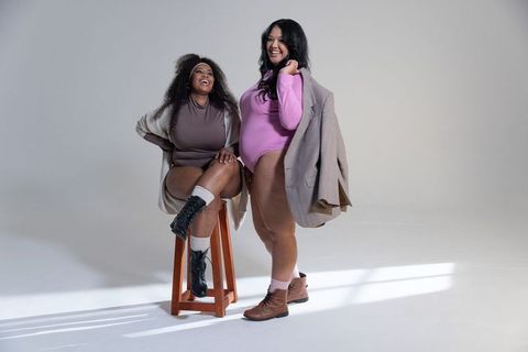 Diverse plus-size women laughing and posing with blazer in minimal studio fashion