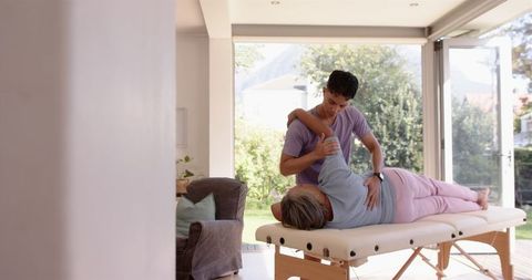 Physiotherapist aiding senior woman with arm exercises in welcoming clinique
