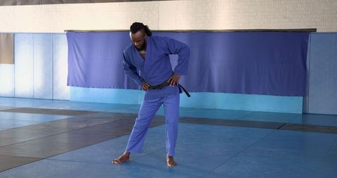 Martial Artist Adjusting Gi Belt in Dojo Training Hall