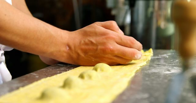 Hands are making fresh homemade pasta by shaping ravioli dough. This captures the process of food preparation, especially traditional Italian cuisine. Ideal for cooking blogs, recipe websites, culinary classes promotional materials, and editorial content focused on homemade food or traditional cooking methods.