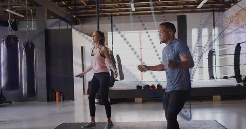 Man and woman jumping rope for boxing cardio training in industrial gym studio