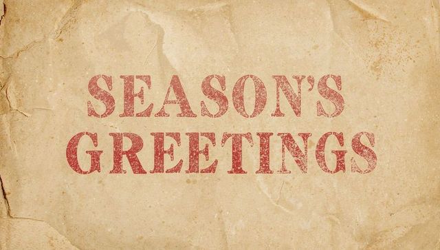 Distressed season's greetings stamped on aged parchment texture for vintage holiday design