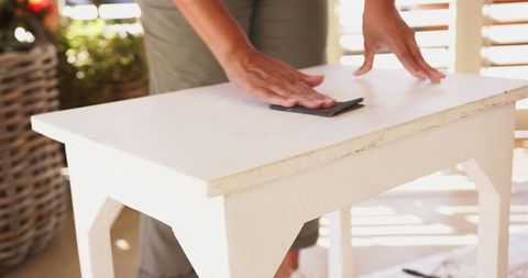 Hands sanding wooden table for diy furniture restoration