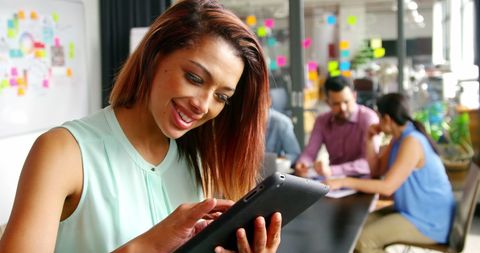 Smiling Businesswoman Engaging with Digital Tablet in Office Environment