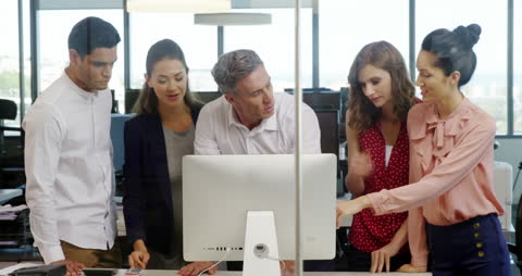 Diverse Team Collaborating Around Computer in Office Environment