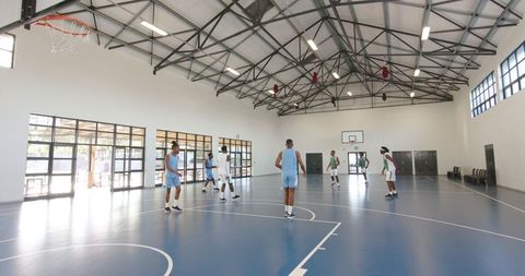 Basketball Players Practicing on Indoor Court with Sunlight Through Windows