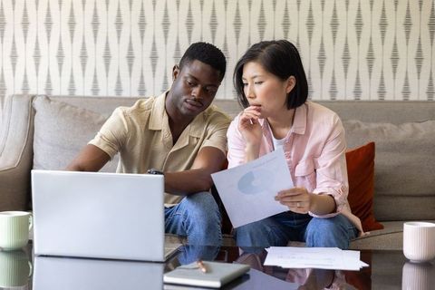 Couple reviewing finances and planning budget together on laptop and documents at home