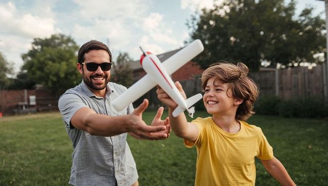 Father and son launching toy airplane in backyard, smiling and playing outdoors
