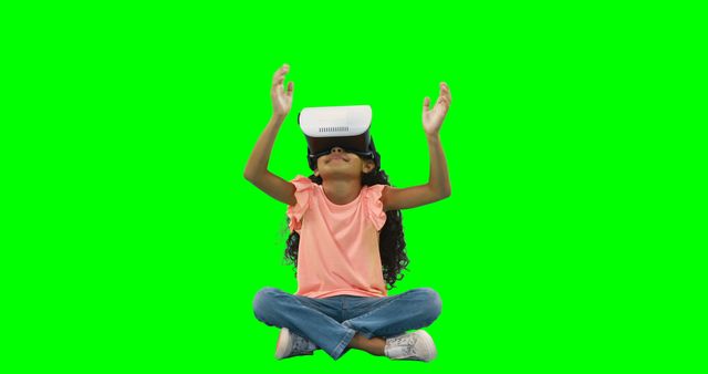A young African American girl is immersed in a virtual reality experience, with copy space. Her arms are raised in excitement or discovery as she interacts with the digital world through her VR headset.