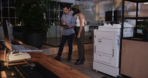 Diverse team collaborating with tablet in modern office at night