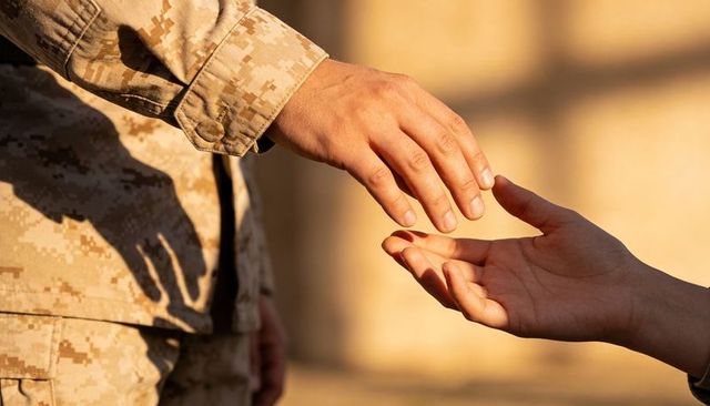 Reaching hands between soldier in camouflage and civilian at golden hour support gesture