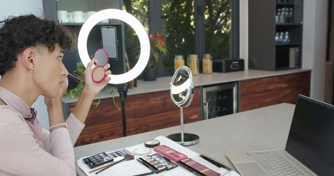 Man making makeup tutorial with makeup kit and ring light