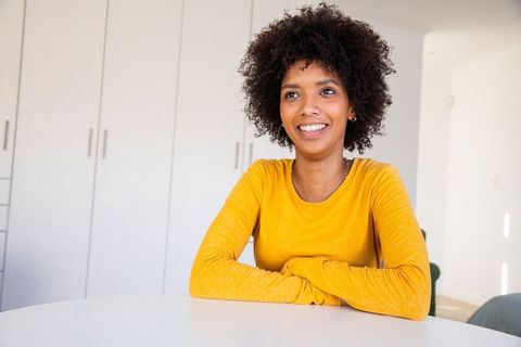 Smiling woman in bright top sitting at dining table