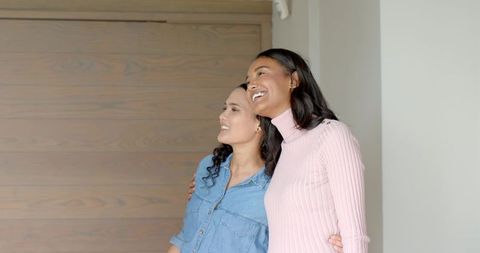 Friends embracing in modern home with wooden accent wall