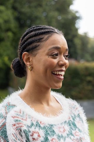 Smiling african american woman looking up in garden wearing fuzzy floral sweater with nose ring
