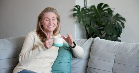 Senior Woman Holding Mug While Relaxing on Comfortable Sofa