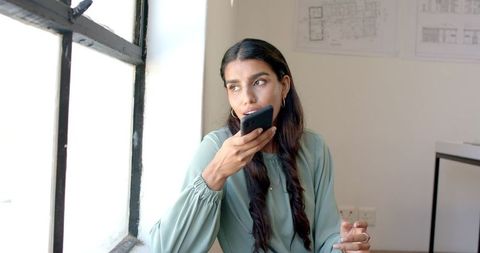 Young Professional Woman Using Voice Control on Smartphone in Office