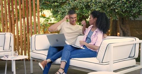 Relaxed couple engaging with technology in garden courtyard
