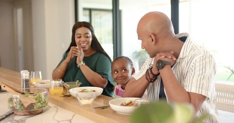 Family sharing sunlit breakfast at kitchen bar smiling and connecting over morning meal