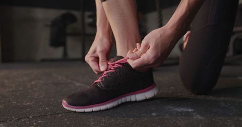 Female Athlete Tying Sport Sneaker Laces in Gym