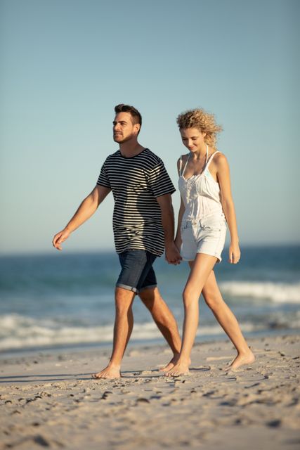 Happy couple walking together hand in hand on the beach