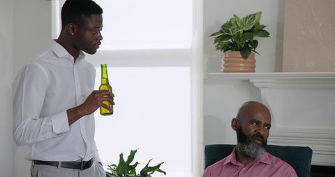 African American Son Holding Drink While Listening to Father at Home