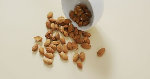 Almonds Spilling from Bowl on Minimalist White Background - Download Free Stock Images Pikwizard.com