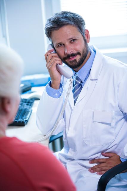Portrait of doctor talking on landline phone in medical office at hospital