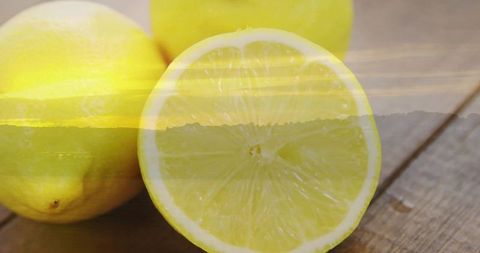 Juicy Halved Lemon with Whole Lemons on Wooden Tabletop