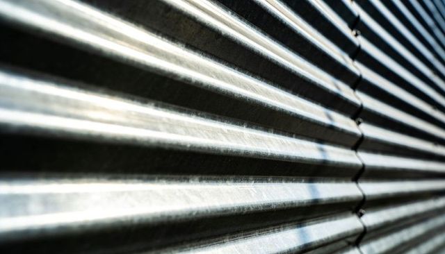 Corrugated galvanized metal panel showing ridges, seam rivets and scuff marks