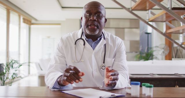 Senior male doctor wearing lab coat and stethoscope provides medical advice at his office desk. Image suitable for healthcare-related content, medical consultations, professional advice articles, patient care brochures, and health education materials.