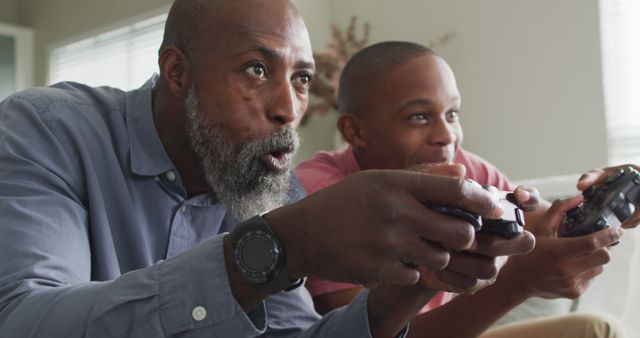 Image of happy african american father and son playing image games. Family, spending quality time together at home.
