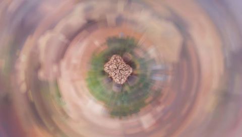 Spinning pastel tiny planet with kaleidoscopic organic core and radial blur motion