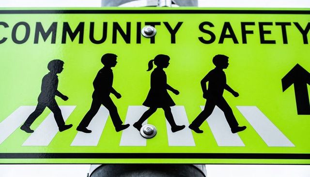 Lime green community safety crosswalk sign featuring children silhouettes walking
