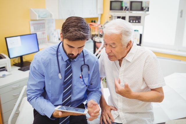 Doctor consulting elderly patient using digital tablet in hospital. Useful for healthcare, medical technology, patient care, and senior health topics. Ideal for illustrating doctor-patient interactions, modern medical practices, and digital health records.