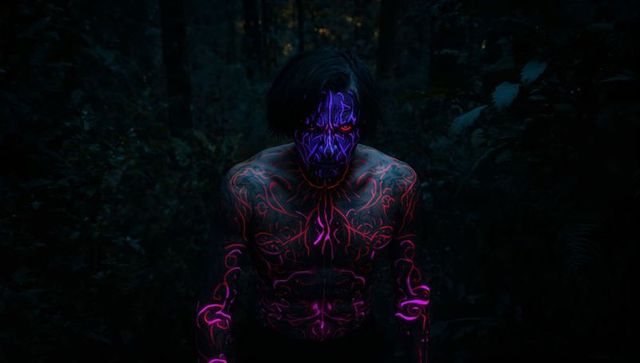 Man with vivid uv neon body paint in mysterious night forest
