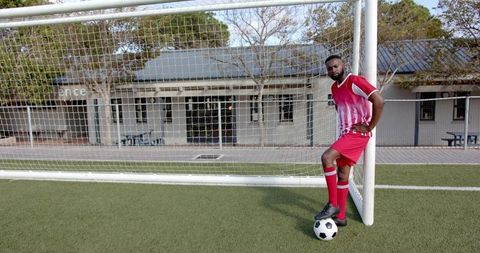 Confident Soccer Player Posing in Front of Goal with Ball