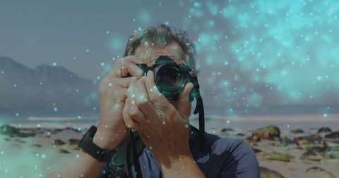 Senior photographer capturing moments with digital camera on beach
