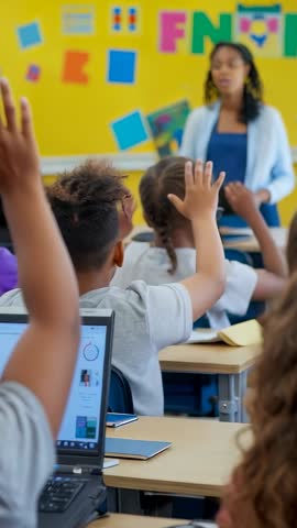 Vertical classroom video of teacher posing question with students raising hands and tablet