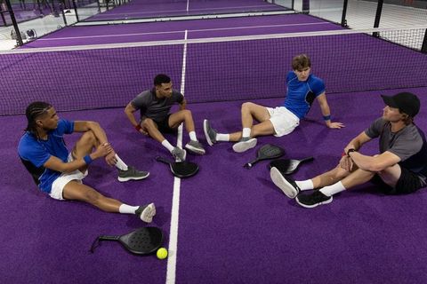 Indoor pickleball team resting on vibrant purple court during postgame break