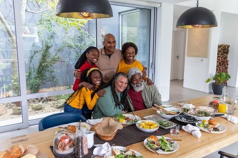 African american multi-generational family sharing joyful meal around wooden dining table