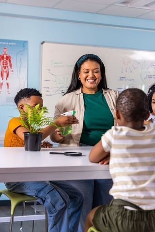 Indian woman teacher guiding african american children in plant experiment
