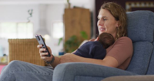 Image of caucasian mother sitting in armchair with newborn baby and using smartphone. motherhood, parental love and taking care of newborn baby concept digitally generated image.