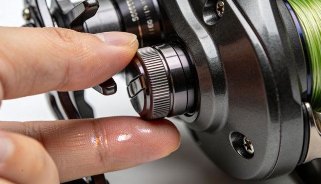 Adjusting baitcasting reel drag knob with fingertips macro close-up of fishing reel control