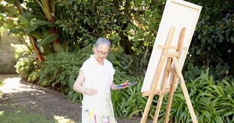 Senior Woman Enjoying Outdoor Painting in Serene Garden