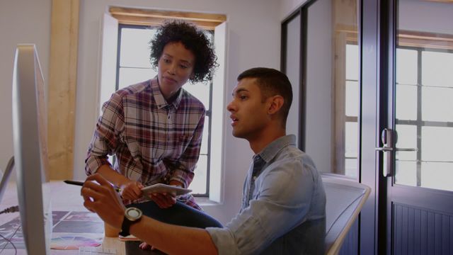 Scene of multiracial colleagues collaborating on a project in a modern office setting. Perfect for use in corporate materials, diversity and inclusion campaigns, teamwork presentations, and business development brochures.