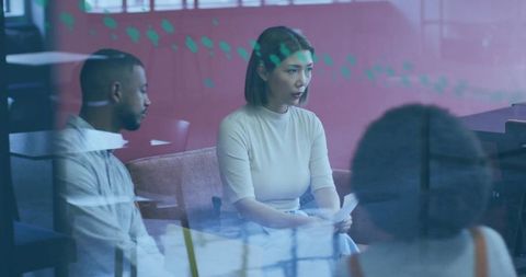 Woman leading team discussion in glass-walled office lounge